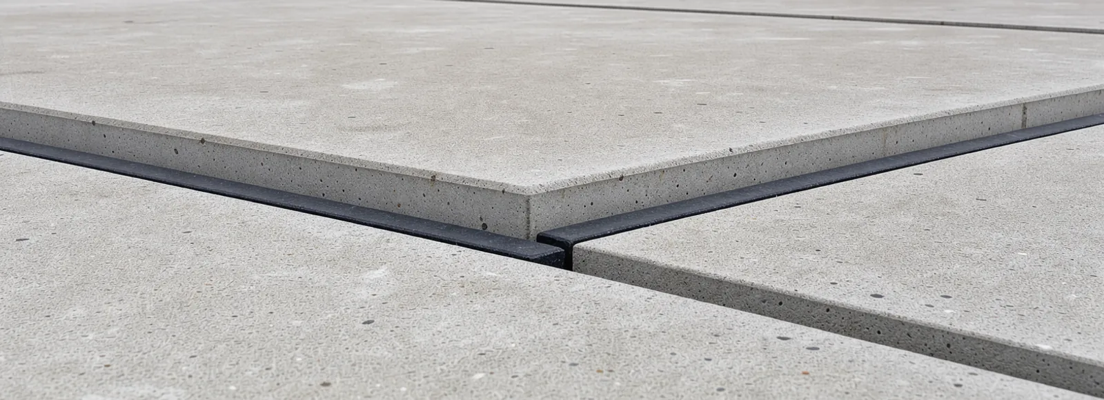 A rubber expansion seal recessed between square concrete edges in daylight.